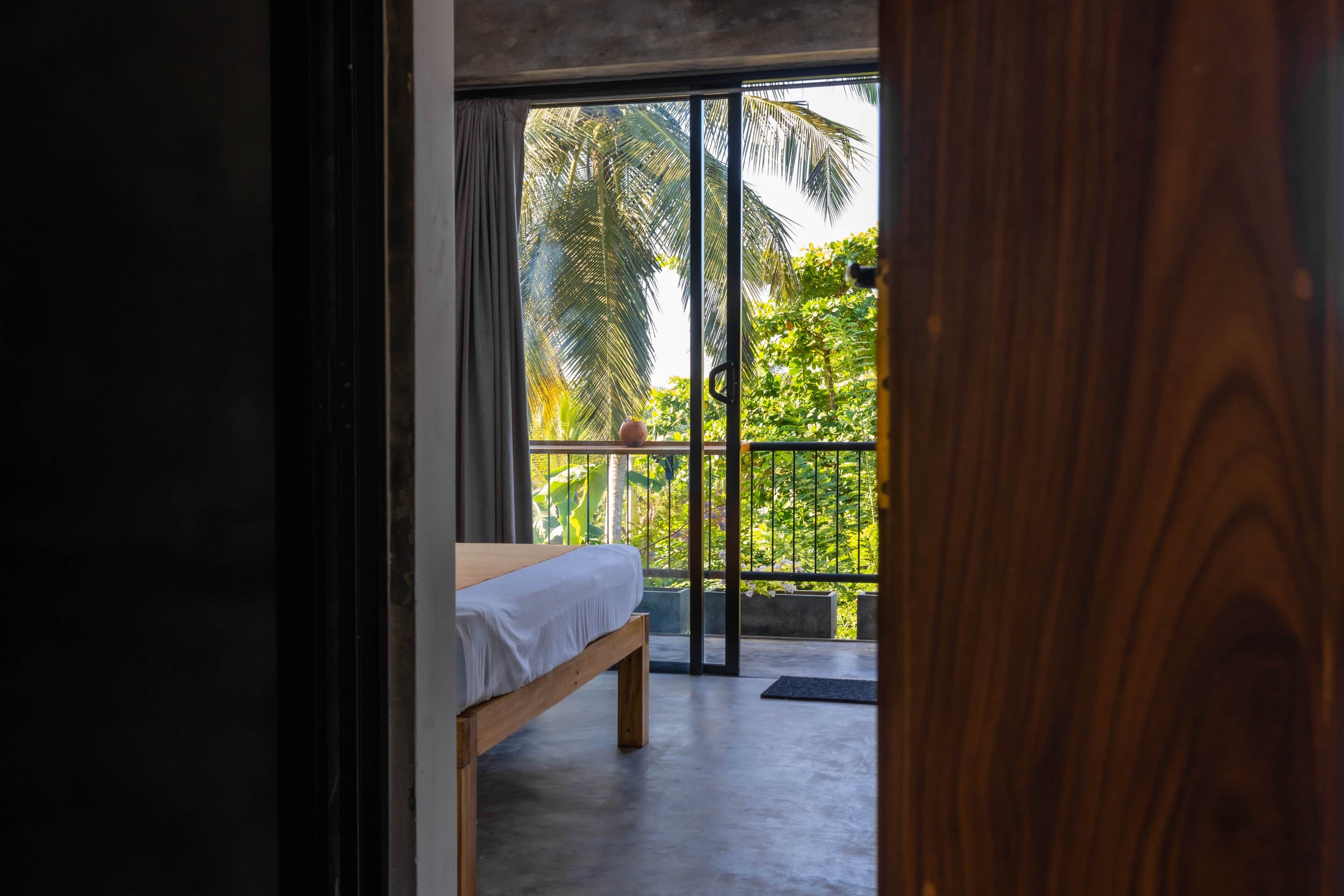 Ein Schlafzimmer mit einem Bett, Balkonblick und Betonboden.