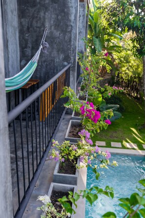 A poolside area with a hammock, flower planters, and a concrete structure.