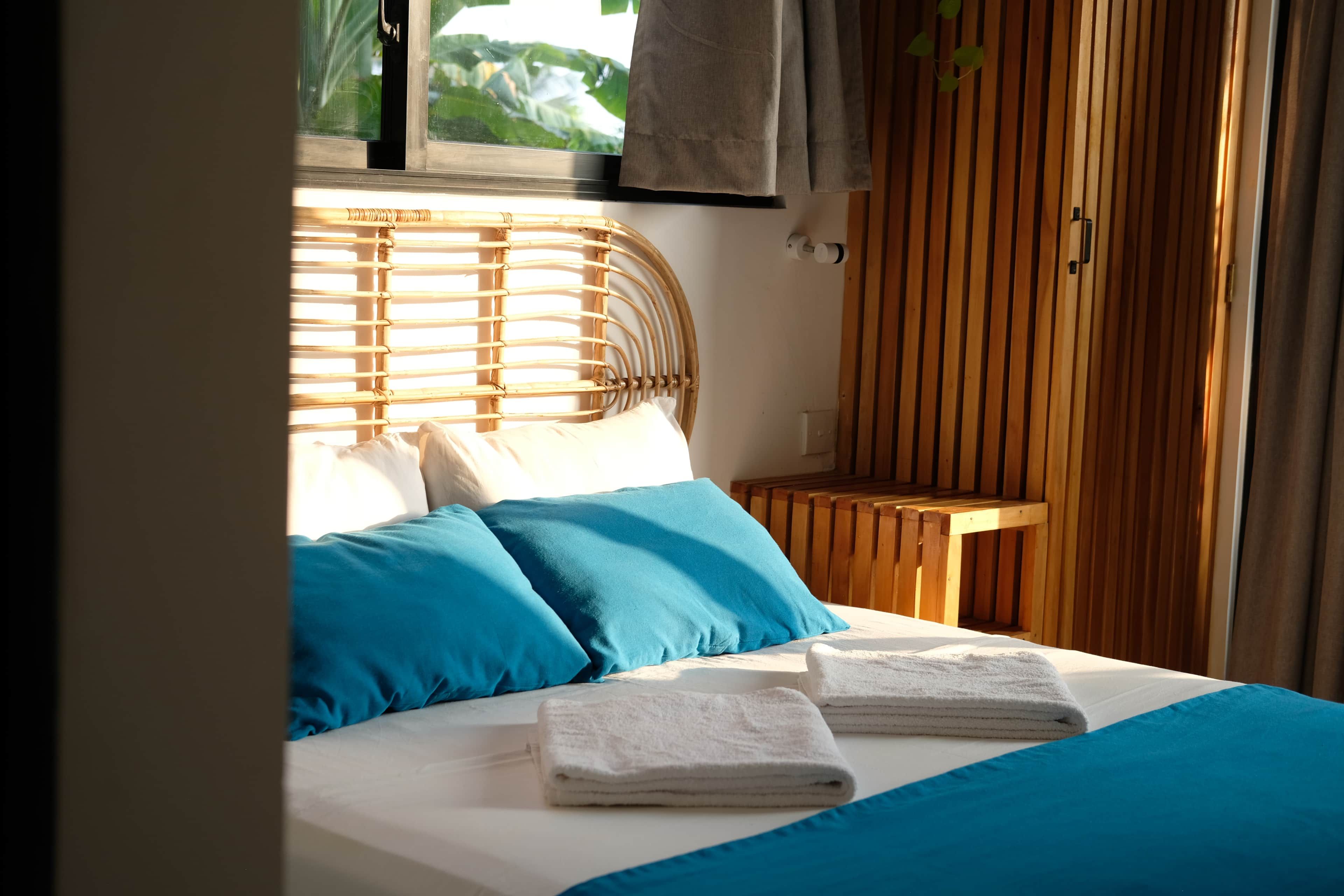 Un letto con lenzuola blu e bianche, una testiera in legno e un comodino in legno con una lampada.