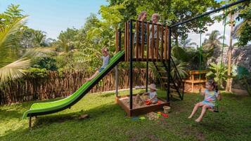 Un'area giochi con scivolo, struttura per arrampicata e altalene.