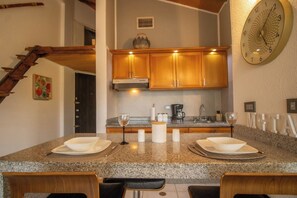 A kitchen with granite countertops, wooden cabinets, a built-in oven, and a clock on the wall.