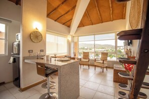 A modern kitchen with a bar area, large windows, and a view of the landscape.