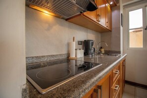 Une cuisine équipée d’une plaque de cuisson intégrée, d’une machine à café et de meubles de rangement en bois.