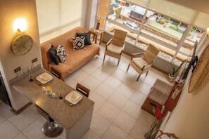 Une chambre d’hôtel moderne équipée d’une kitchenette, d’un canapé, d’une table à manger et offrant une vue sur la rue.