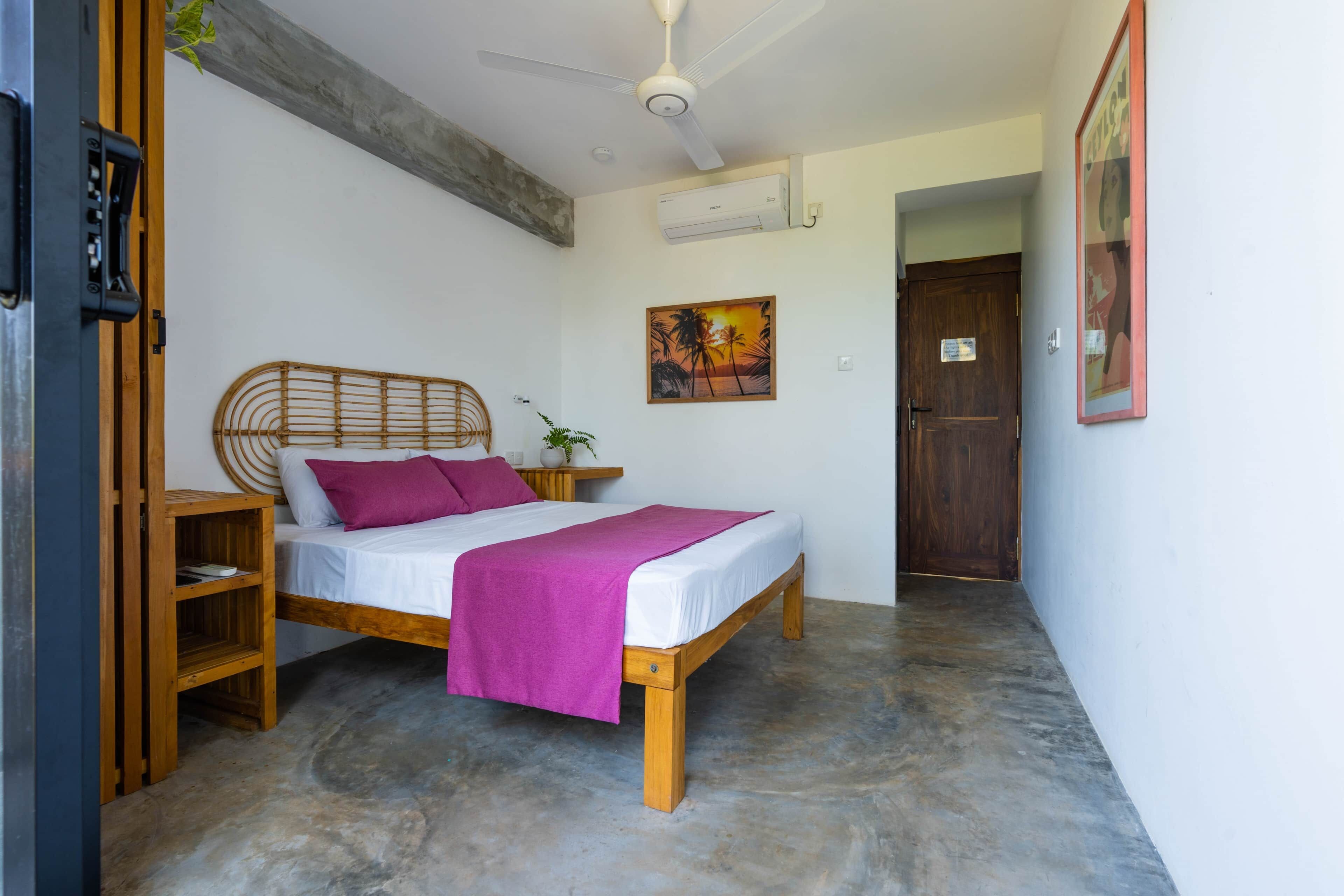 Ein Schlafzimmer mit einem hölzernen Bett, einem Deckenventilator, einem Gemälde und einer Tür.