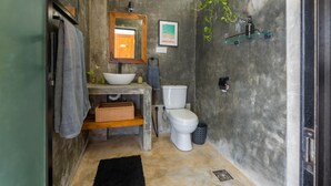 A bathroom with a wooden vanity, a white sink, a toilet, and a shower area. - The Orchid Room (Maaliyadda)
