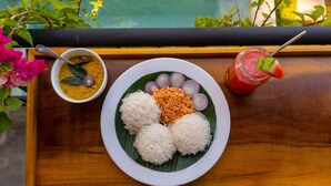 A plate of food with white rice, a bowl of soup, and a drink on a wooden table. - The Orchid Room (Maaliyadda)