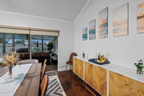 A modern dining area with a wooden table, chairs, and a view of the outdoors through large sliding doors. - Waterfront Escape: 5Bed, 3Bath, Heated Pool! (Tampa)