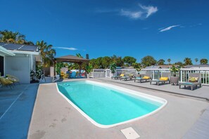 A swimming pool with lounge chairs and a covered seating area. - Waterfront Escape: 5Bed, 3Bath, Heated Pool! (Tampa)