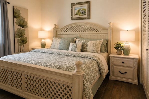 A bedroom with a bed, nightstands, a dresser, a painting, and a window with blinds.