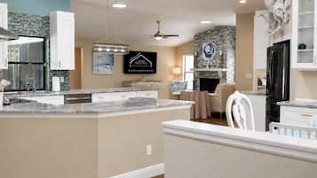 A modern kitchen with a central island, white cabinetry, and a stone backsplash.
