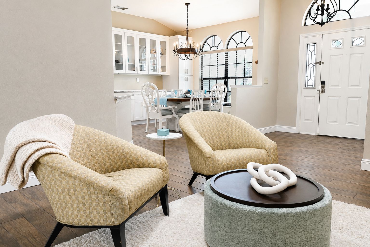A living room with two armchairs, a round coffee table, and a decorative sculpture.