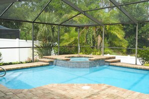 A swimming pool with a hot tub, surrounded by a covered area with a metal frame and glass panels. - Serene Pool & Lake Retreat Sleeps8 Tarpon Springs (Tarpon Springs)