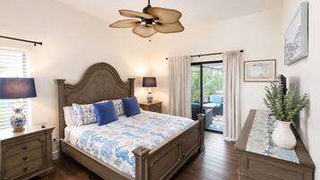 A bedroom with a bed, nightstands, a ceiling fan, a window with blinds, a view of the outdoors, and a potted plant.