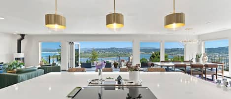 A spacious kitchen with a central island, large windows offering a scenic view, and three pendant lights.
