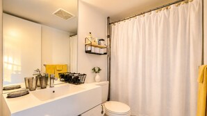 Un baño moderno con un lavamanos blanco, un inodoro y una cortina de ducha.