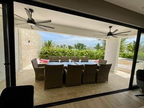 A room with a sliding glass door leading to an outdoor patio area with a dining table and chairs. - The Beach - Crystal Lagoon Waterfront - Sleeps 10 (Punta Cana)