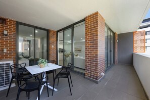 Ein Balkon mit Tisch und Stühlen, einem Blumentopf und Blick auf eine Wohngegend.