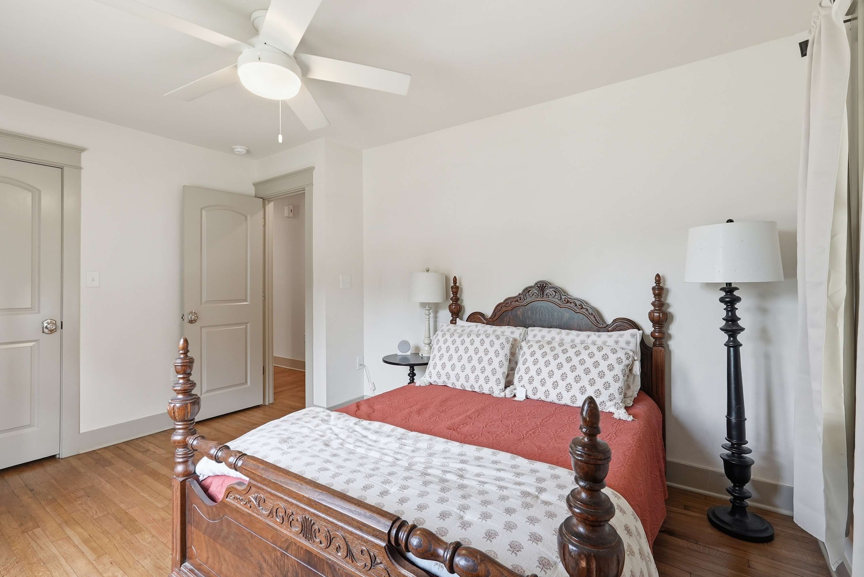 A bedroom with a wooden bed, a ceiling fan, and a bedside table.