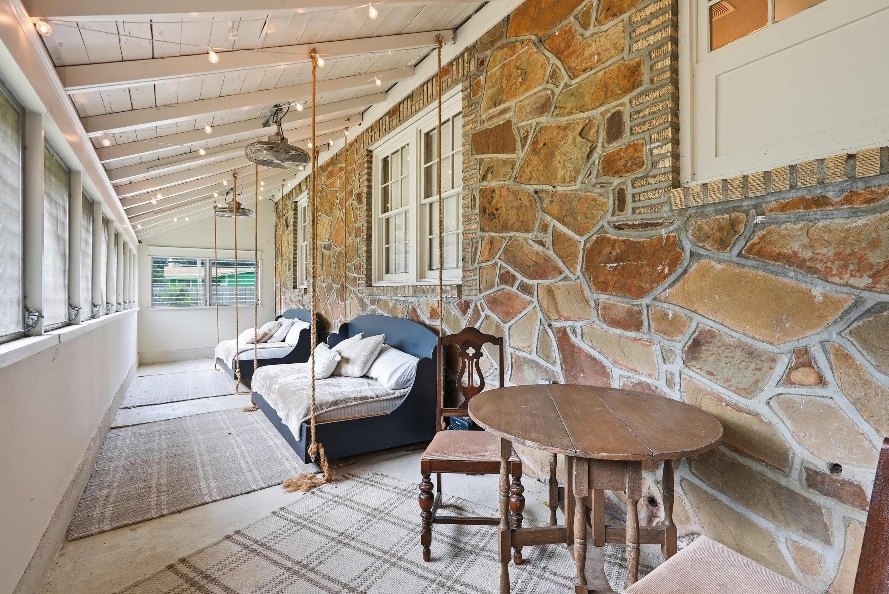 A room with a stone wall, a bed, a chair, and a table.