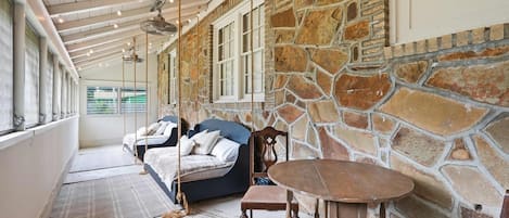 Una habitación con pared de piedra, una cama, una silla y una mesa.