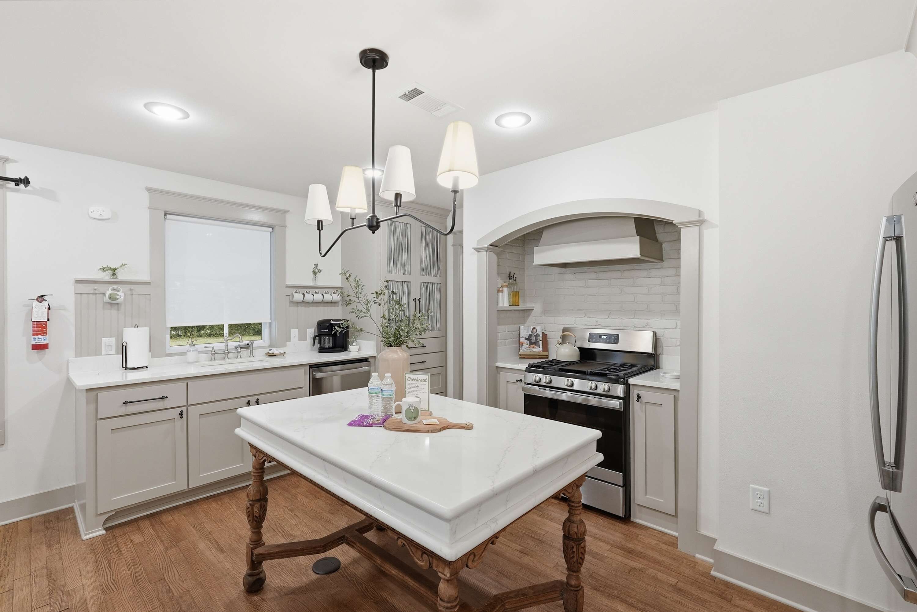 A modern kitchen with a central island, white cabinetry, and a stainless steel range hood.