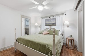 A bedroom with a bed, a ceiling fan, a window with a view, and a bedside table with a lamp. - Respite Cottage - Front Porch - Sunroom - 1 mi UCA (Conway)