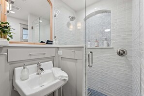 A bathroom with a white sink, mirror, and shower. - Respite Cottage - Front Porch - Sunroom - 1 mi UCA (Conway)