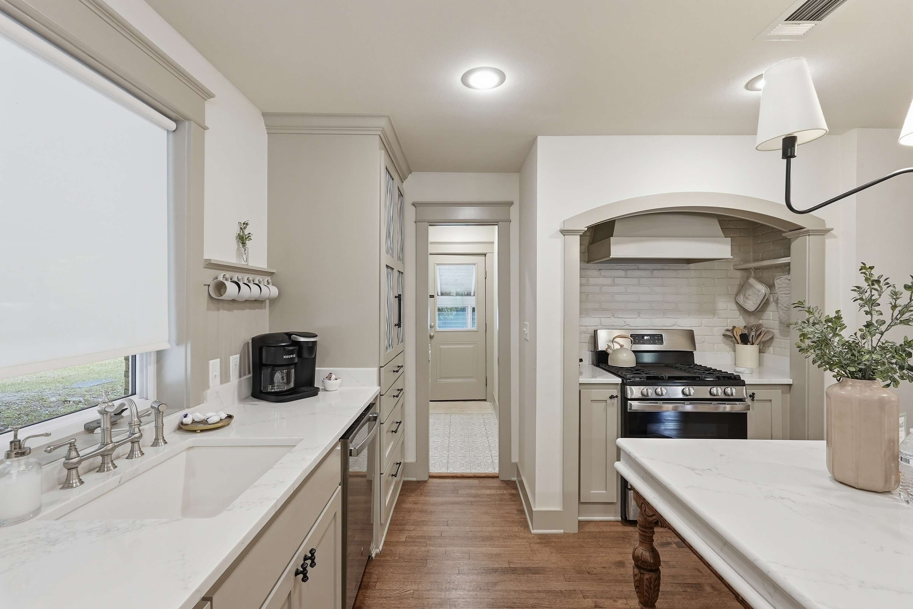 A modern kitchen with a built-in oven, a coffee maker, and a view through the window.