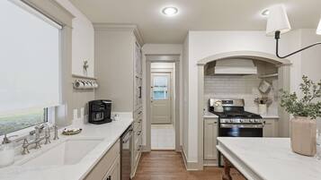 A modern kitchen with a built-in oven, a coffee maker, and a view through the window.