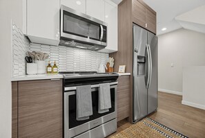 Une cuisine moderne équipée d’appareils électroménagers en acier inoxydable, notamment un four à micro-ondes, un four et un réfrigérateur.