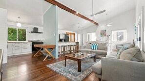 A spacious living area with a wooden coffee table, a sofa, and a dining table with bar stools. - Tropical Retreat on Reid (Wongaling Beach)