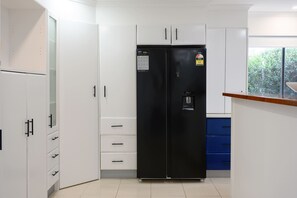 Eine Küche mit weißen Schränken, einem schwarzen Kühlschrank und einer blauen Arbeitsplatte.