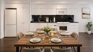 Una cocina moderna con armarios blancos, encimera negra y una mesa de comedor preparada para seis comensales.