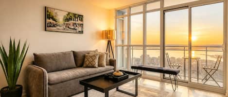 Una sala de estar moderna con sofá, mesa de centro y un amplio ventanal con vista a la ciudad.