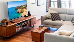 Een woonkamer met een flatscreen televisie, een houten dressoir, een bank en een salontafel.