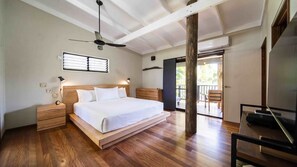 A bedroom with a wooden bed, bedside tables, a ceiling fan, a window with blinds, and a view of the outdoors. - Island Vista Retreat (South Mission Beach)