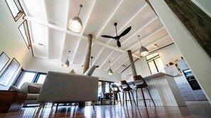 A spacious living area with a high ceiling, multiple hanging lights, and a ceiling fan. - Island Vista Retreat (South Mission Beach)