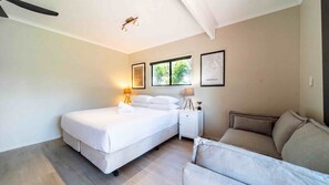 A bedroom with a bed, bedside lamps, a nightstand, a window with a view, and a framed map on the wall. - Island Vista Retreat (South Mission Beach)