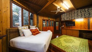 A wooden room with a bed, a television, and a large window. - The Rainforest Nook Cairns (Kamerunga)