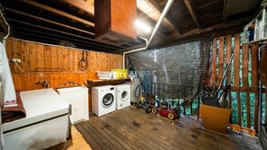 Ein Waschraum mit Waschmaschine, Trockner und einem kleinen Wäschewagen.