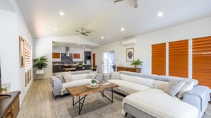 A modern living room with a sofa set, a wooden coffee table, and a kitchen in the background. - The Retreat - South Mission Beach (South Mission Beach)