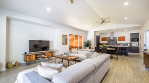 Una sala moderna con un televisor de pantalla plana grande, un mueble de entretenimiento de madera y un sofá seccional gris.