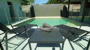 A poolside area with lounge chairs and towels, surrounded by glass walls and a wooden fence. - The Retreat - South Mission Beach (South Mission Beach)