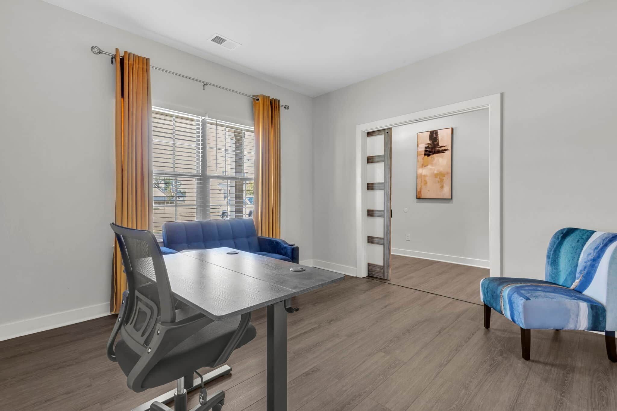 Quarto moderno com mesa de jantar, sofá azul e uma cadeira.