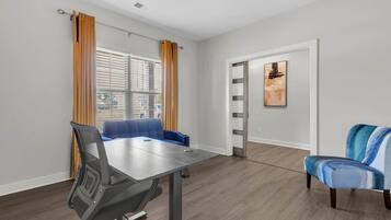 Quarto moderno com mesa de jantar, sofá azul e uma cadeira.