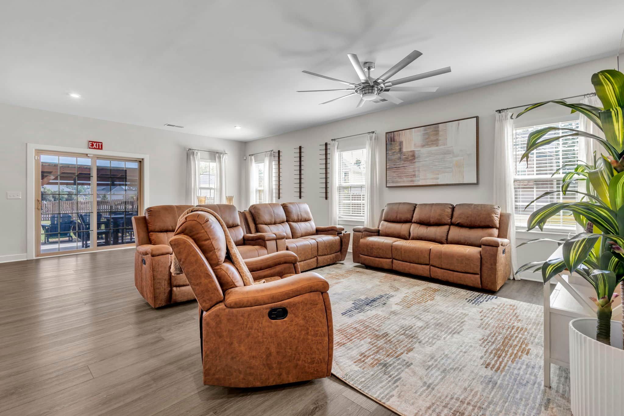 Un salon spacieux avec un canapé d’angle, un fauteuil inclinable et un ventilateur de plafond.