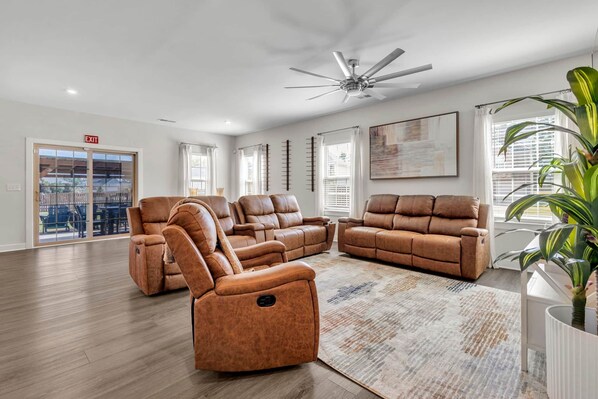 A spacious living room with a sectional sofa, a recliner, and a ceiling fan.