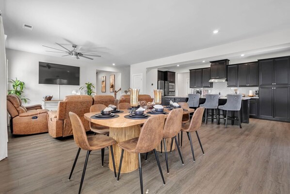 Una sala moderna con comedor, cocina y ventilador de techo.