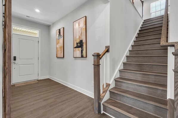 A staircase with wooden steps and a handrail, leading to a landing with two framed artworks on the wall.